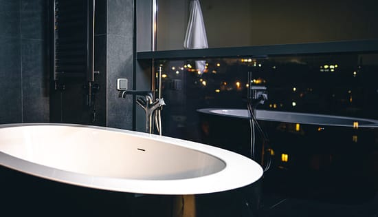 Interior of a modern bathroom with a window overlooking the city. The interior of a modern bathroom with a window overlooking the night city, copy space.